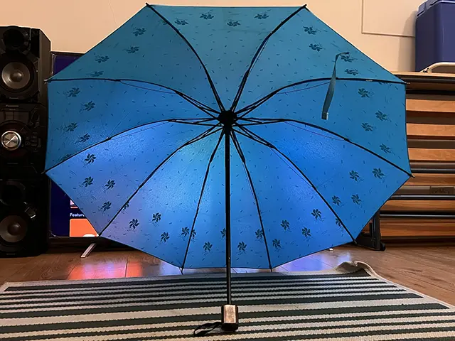 Blue compact umbrella open on a mat